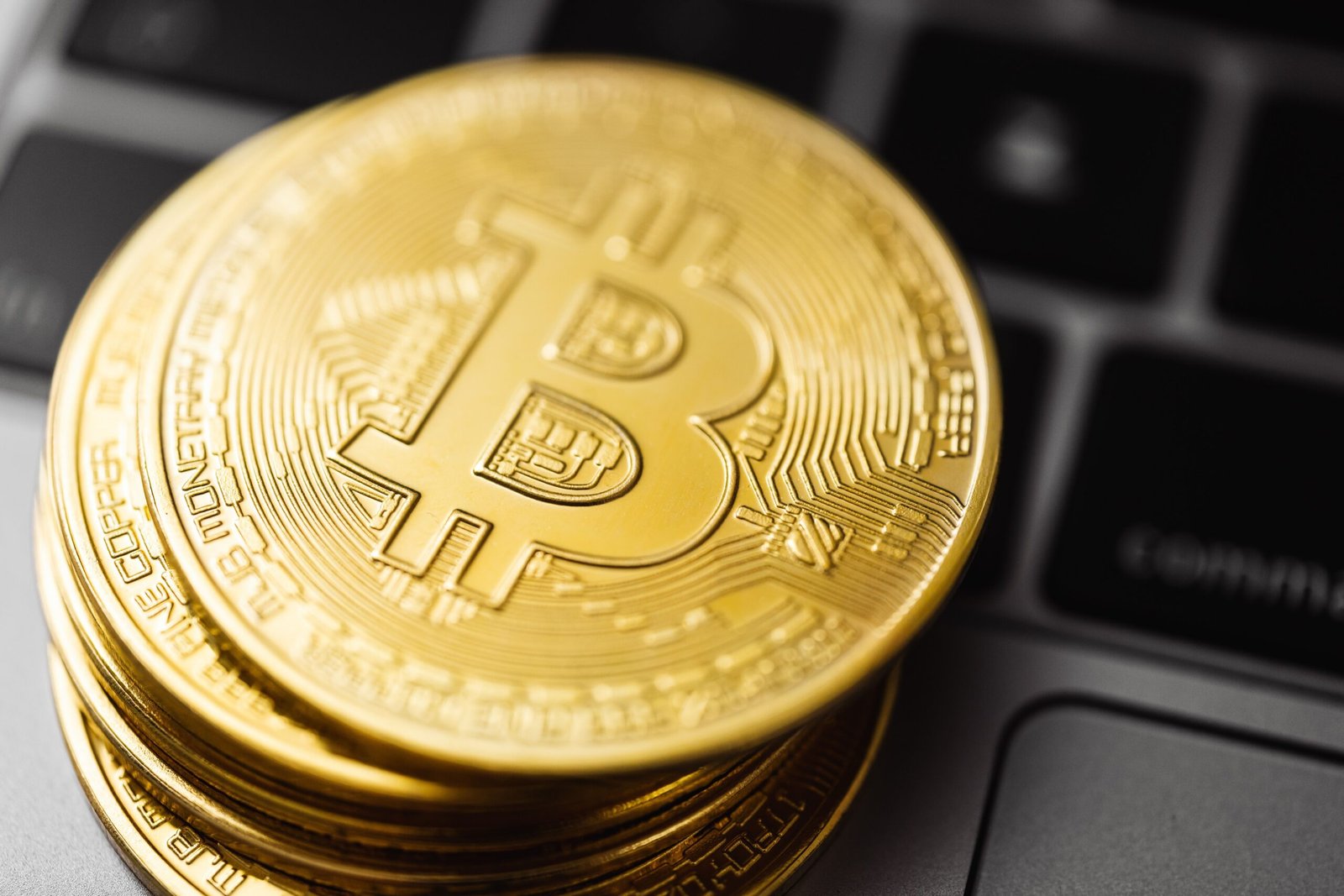 Moedas de bitcoin sobre teclado de notebook, simbolizando ativos digitais